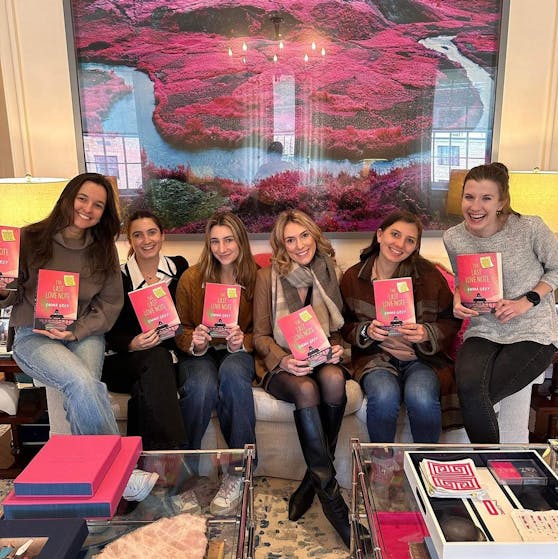 Six women sitting on a long couch, and one of them is Emma Grey's daughter. They are all holding the book 'The Last Love Note'.