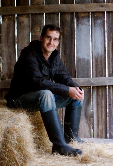 Chef Rodney Dunn sitting in a barn on a pile of hay. 